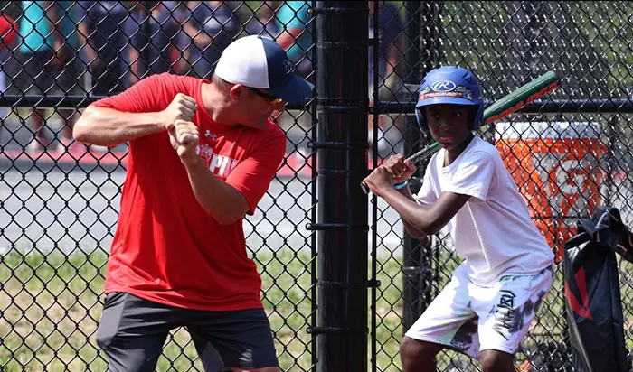 An older man teaching a young boy how to hold a baseball bat