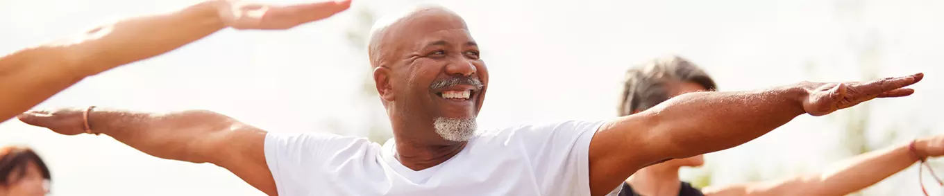 A black man smiling performing yoga.