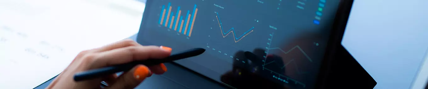 A photo of a woman with vibrant orange nails checking the data on her tablet.