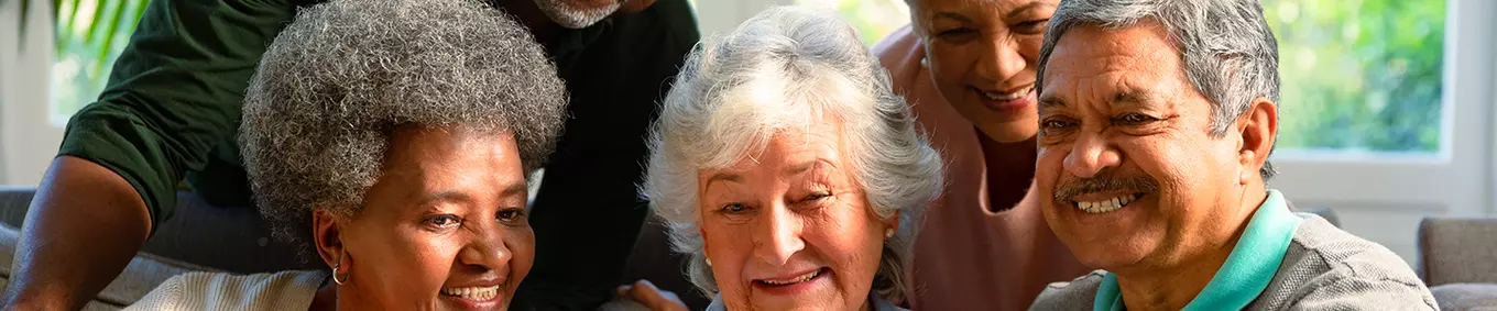A diverse group of elderly people smiling looking at a pamphlet.