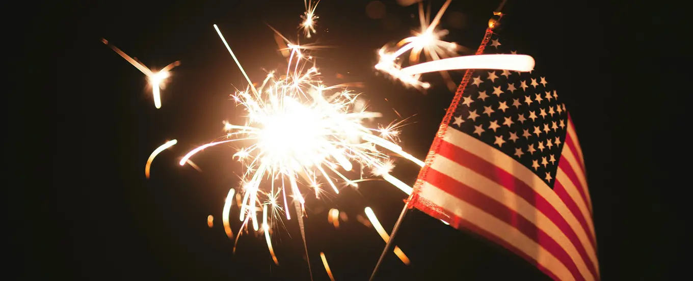 fireworks and american flag against night sky