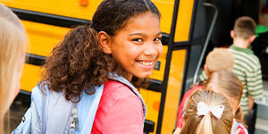Smiling girl getting on schoolbus