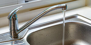 A silver kitchen sink with running water.