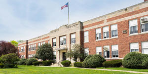 School Building front entrance, with flag and sidewalk