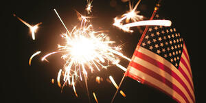 fireworks and american flag against night sky