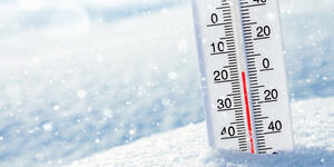 Thermometer with a low temperature sticking out of the snow