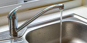 A silver kitchen sink with running water.