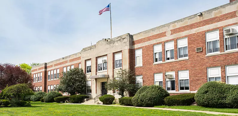 School Building front entrance, with flag and sidewalk