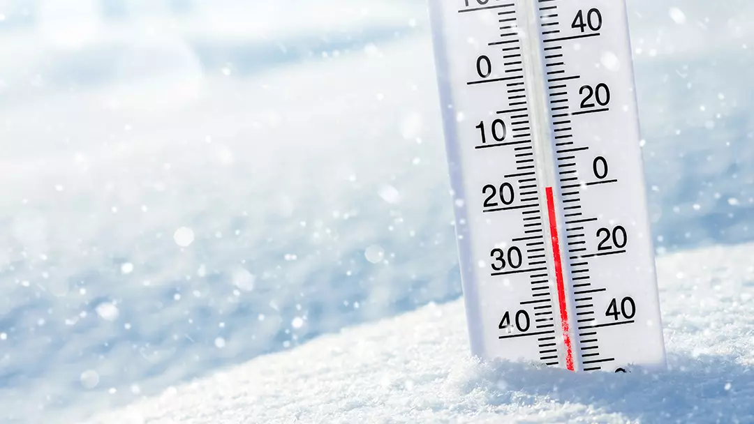 Thermometer with a low temperature sticking out of the snow