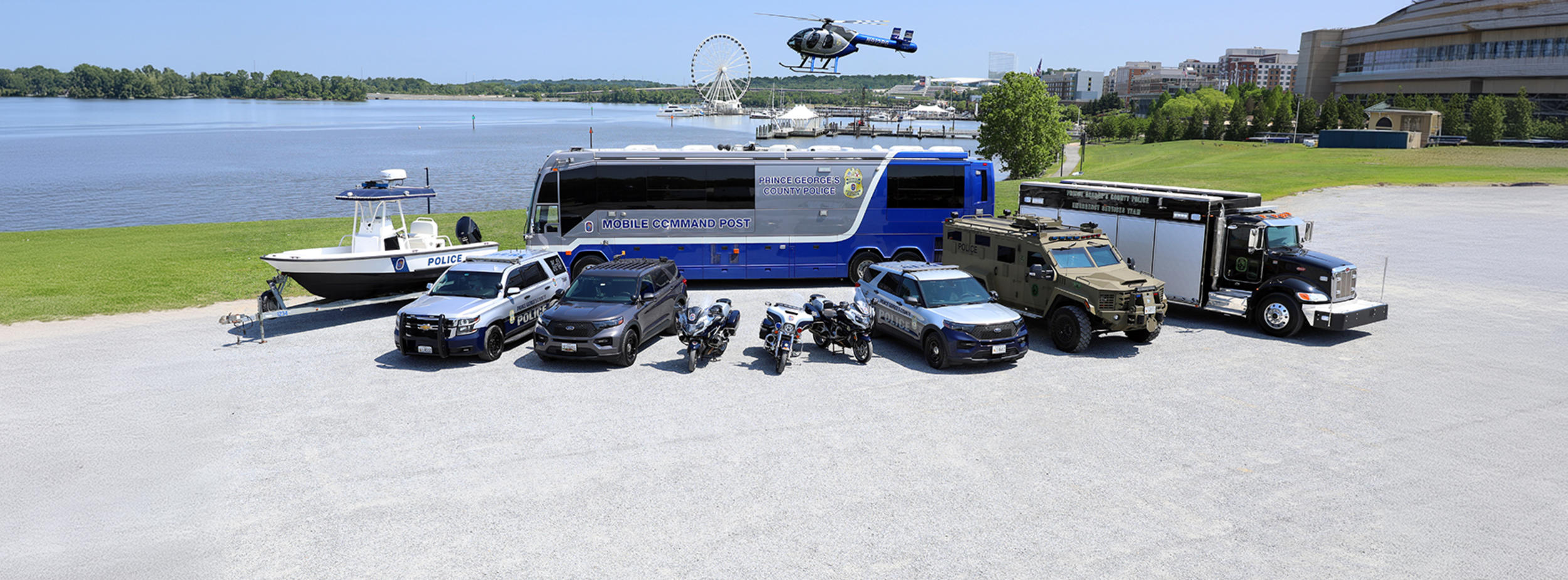 A collection of various means of transportation used for Prince George's County Police Department (boat, Ford Interceptors, motorcycles, bus, armored vehicle, & law enforcement truck)