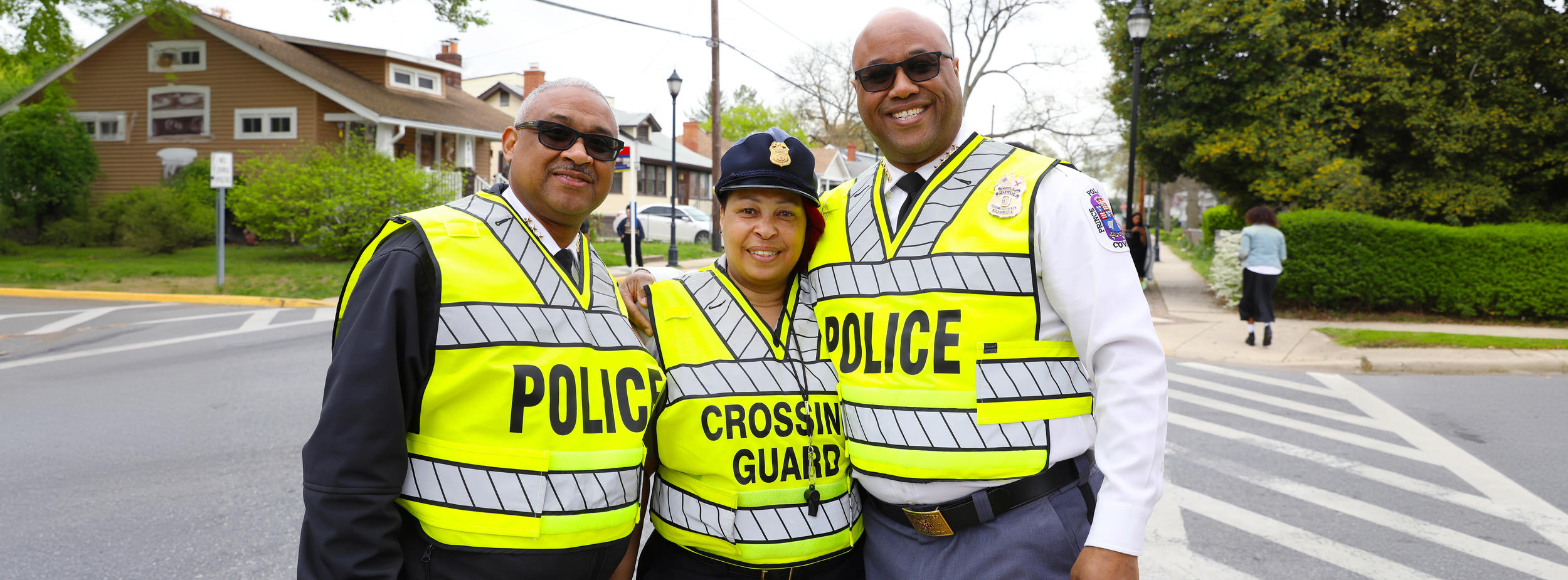 2 Police Officers and 1 Crossing Gaurd huddled together in a group photo