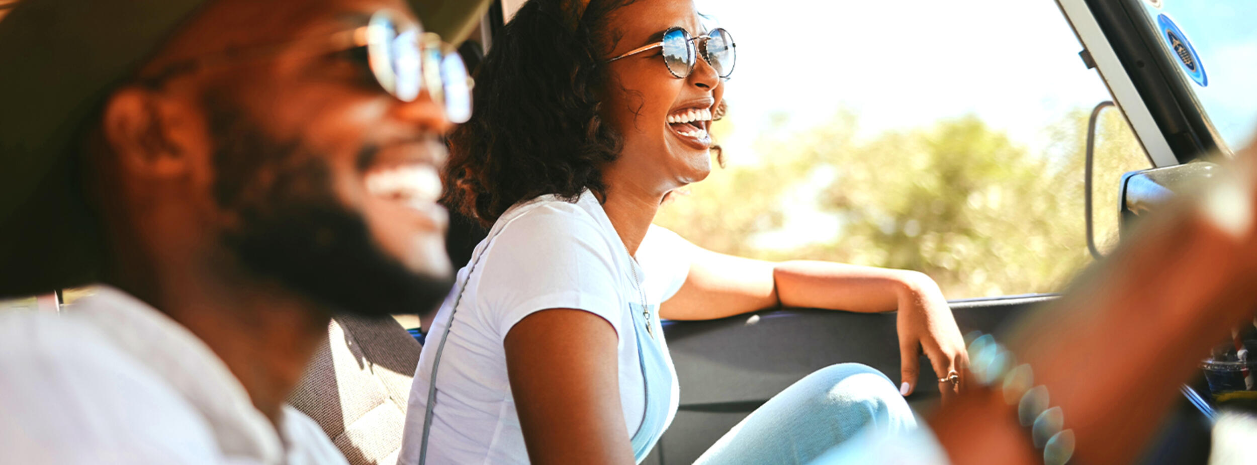 Smiling people riding in the car on a sunny day