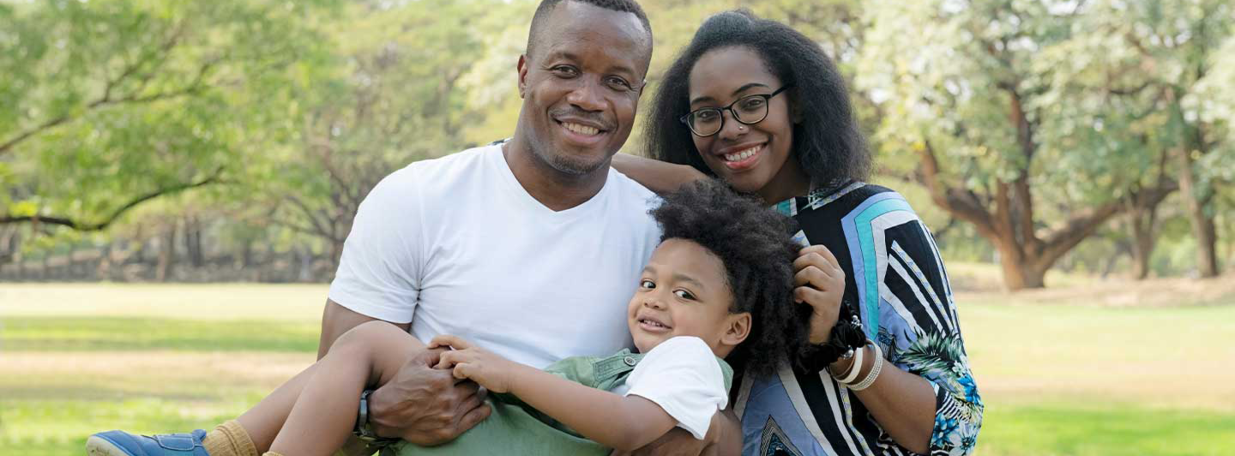 A father, a mother, and their child smiling 