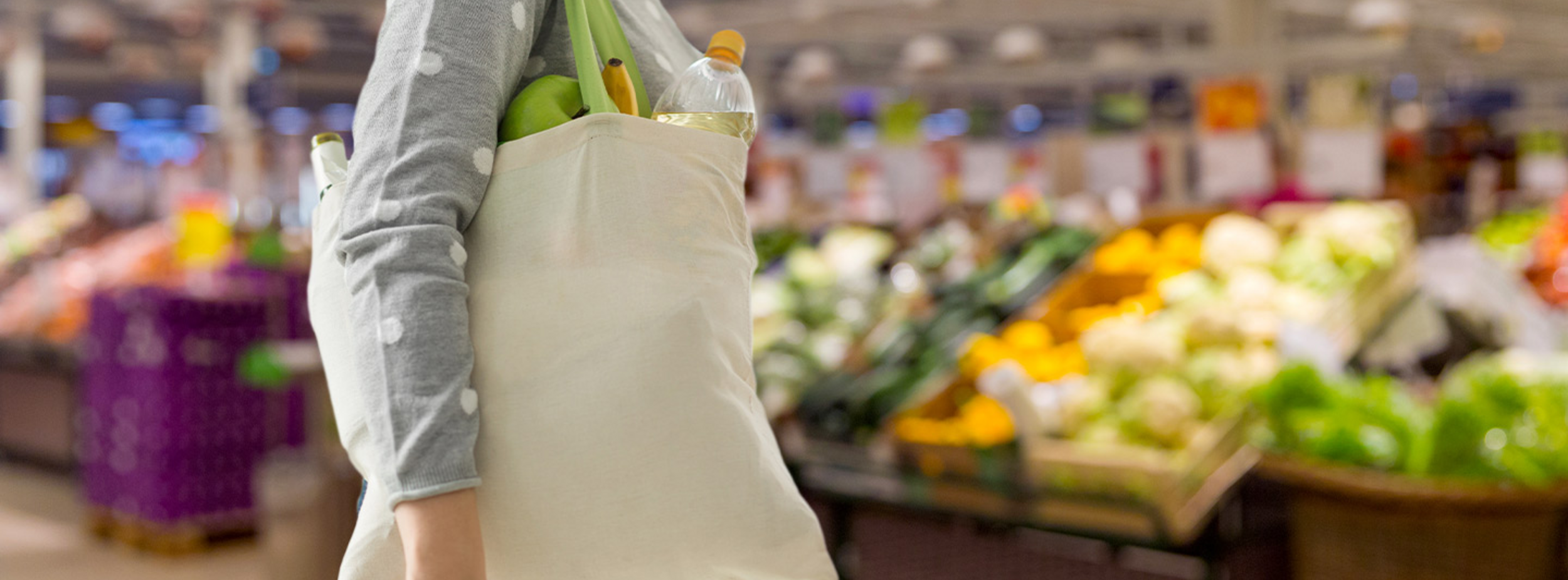 grocery shopper carrying a reusable bag in the produce section