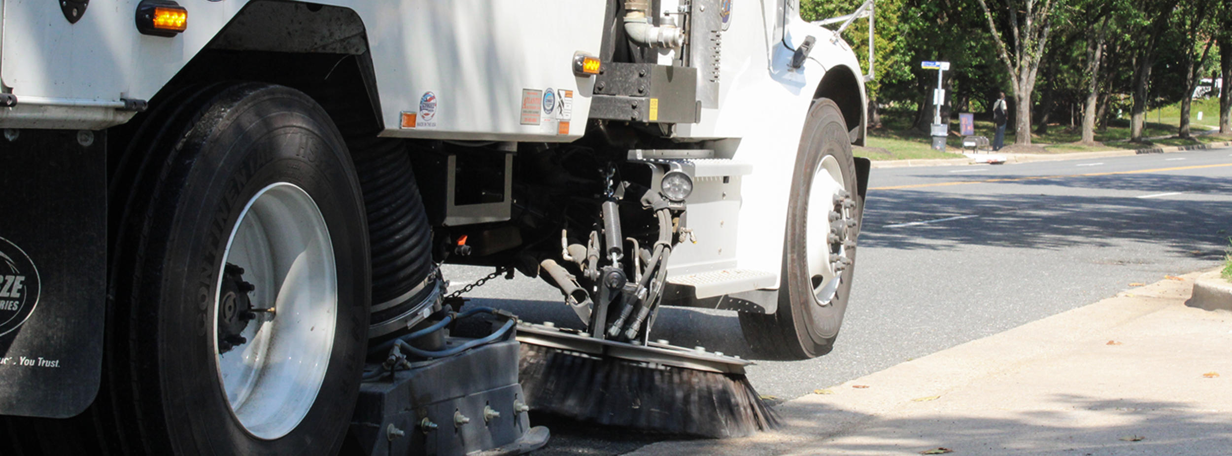 Big white truck performing residential street sweeping on a road